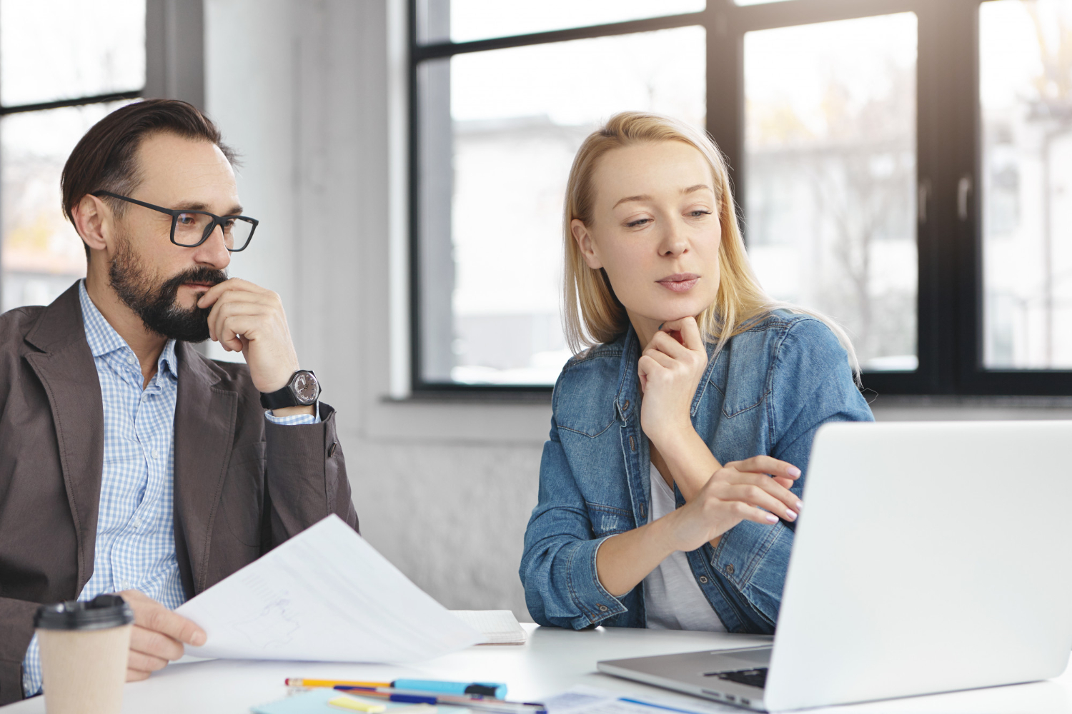 Deux personnes regardant un ordinateur et discutant de manière concentrés