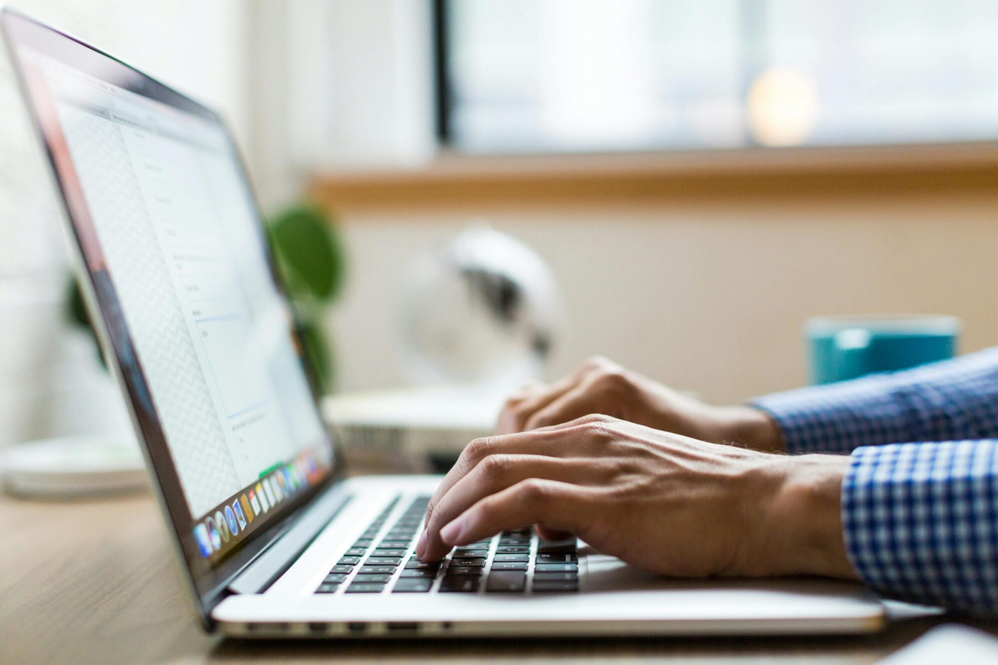 Vue de profil d'un ordinateur avec deux mains en train d'écrire sur le clavier