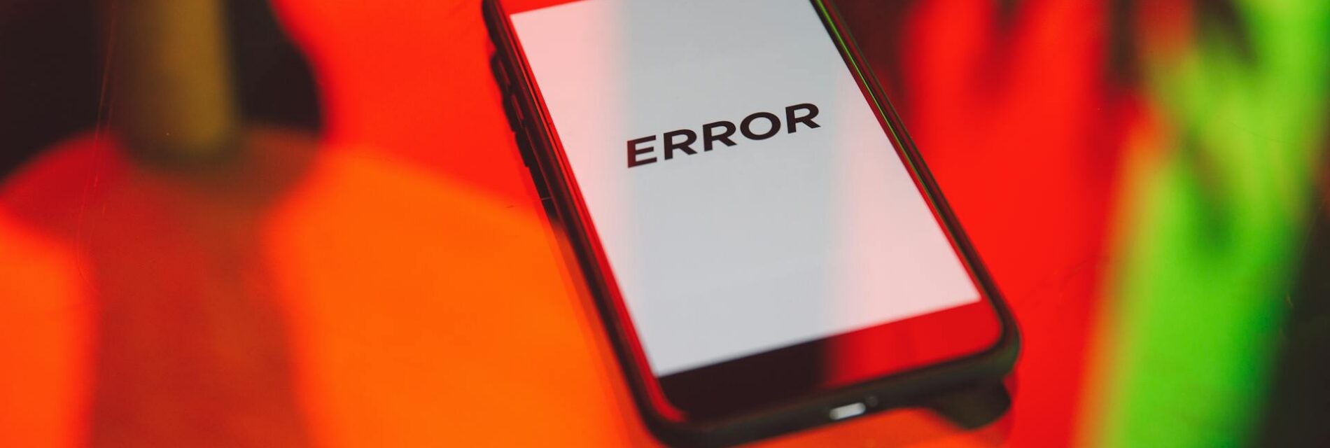 Téléphone indiquant sur son écran le mot error posé sur une table réfléchissant des couleurs rouge et verte