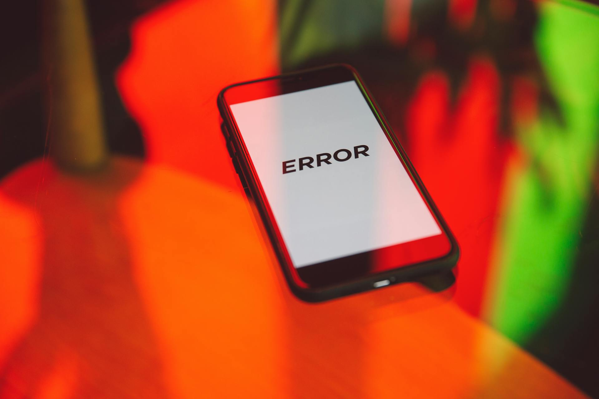 Téléphone indiquant sur son écran le mot error posé sur une table réfléchissant des couleurs rouge et verte