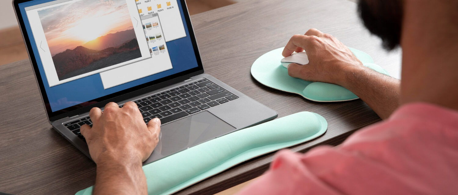Homme travaillant à un ordinateur et visionnant une image, une main sur le clavier, l'autre sur sa souris