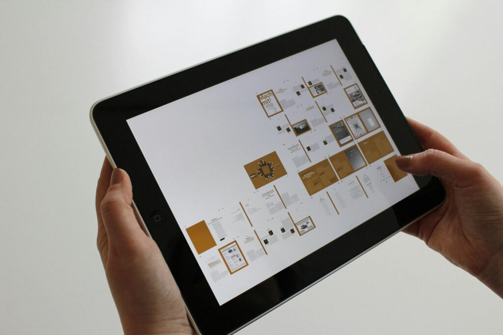 Tablette tenu dans deux mains présentant une maquette éditoriale