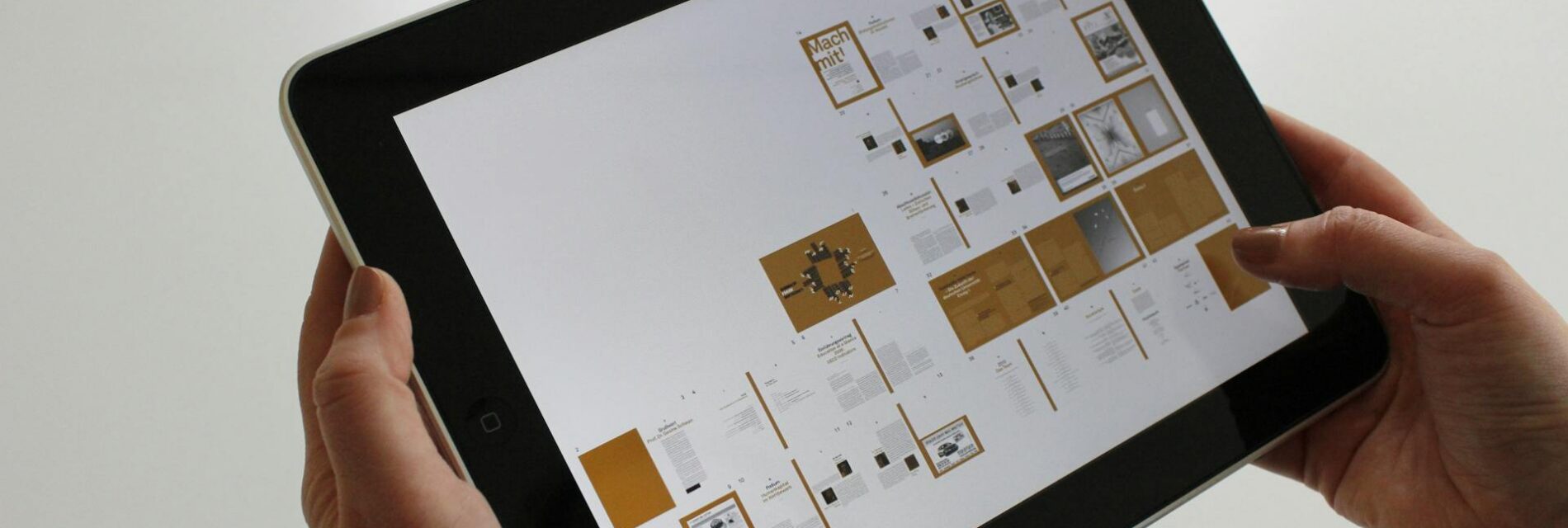 Tablette tenu dans deux mains présentant une maquette éditoriale