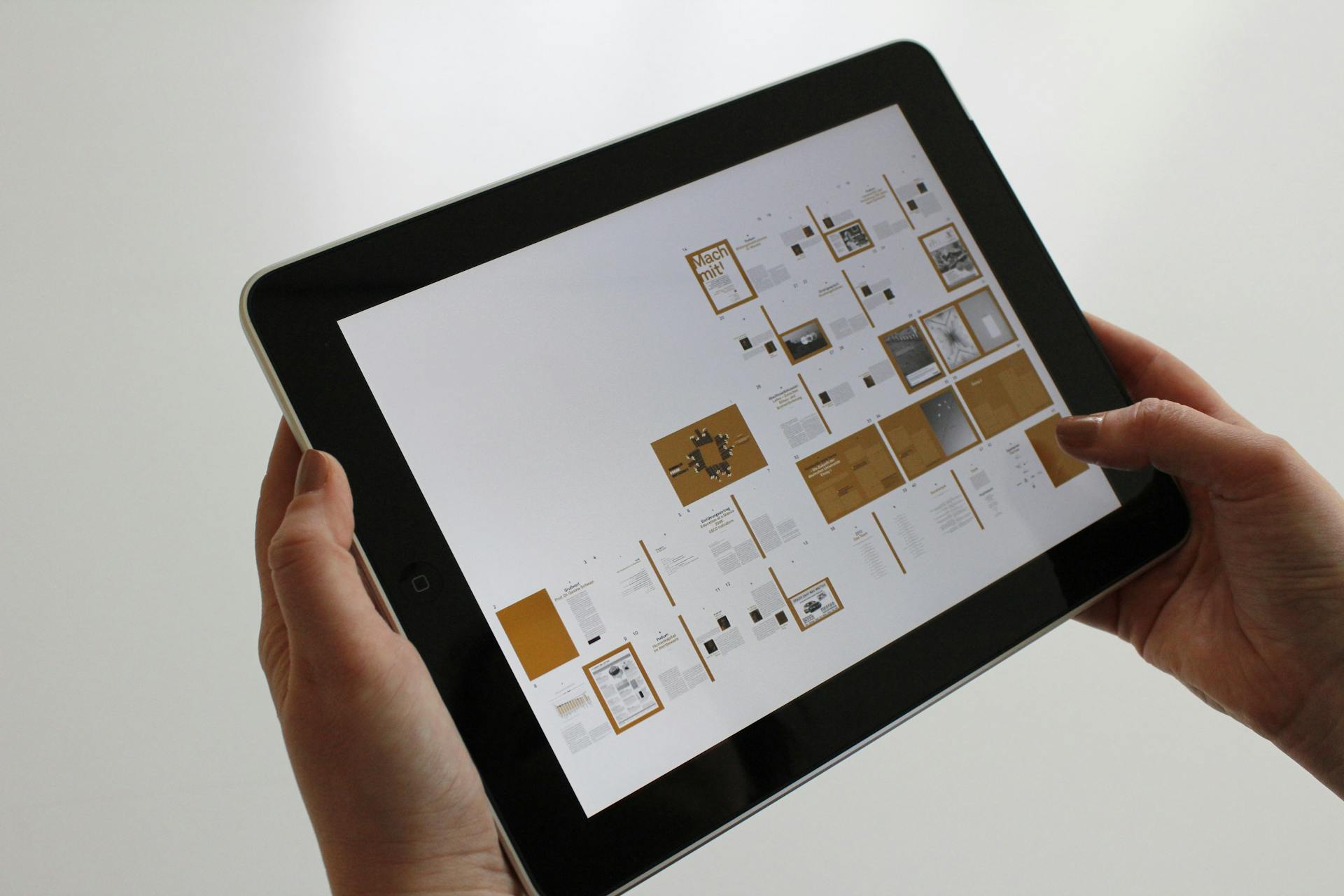 Tablette tenu dans deux mains présentant une maquette éditoriale